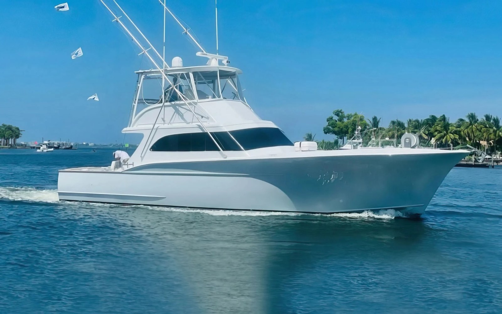 White yacht cruising on a sunny day with clear blue sky and palm trees.
