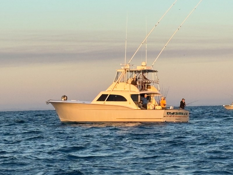 Fishing boat with antennas on ocean at sunset.