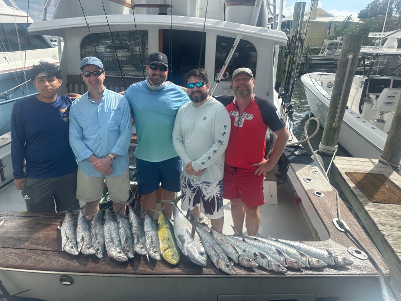 Five men on a boat with a display of caught fish.